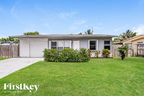 a small white house with a yard and grass