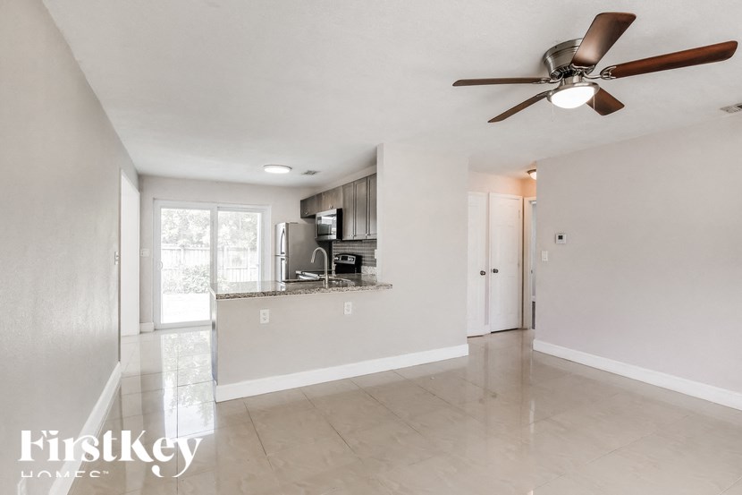 an empty living room and kitchen with a ceiling fan