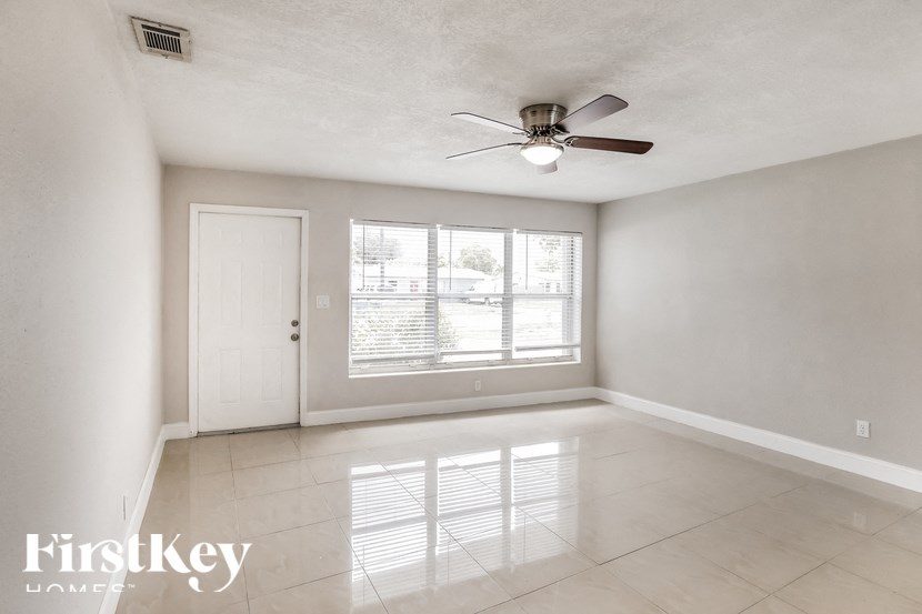 an empty living room with a ceiling fan and a window