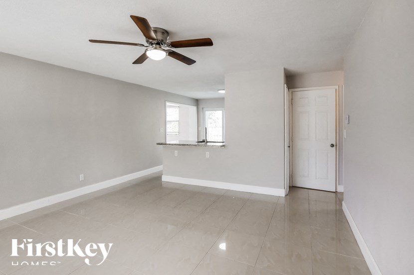 an empty living room with a ceiling fan and a window