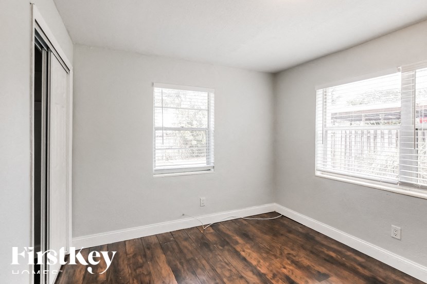 a bedroom with wood flooring and two windows