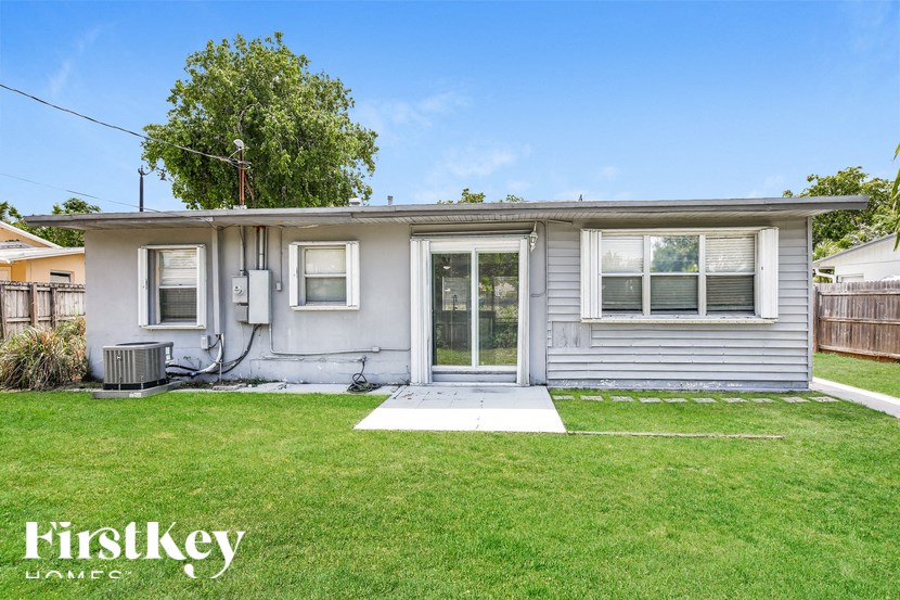 a small gray house with a grassy yard and a porch