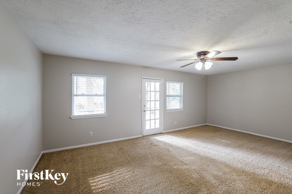 an empty living room with a ceiling fan and window