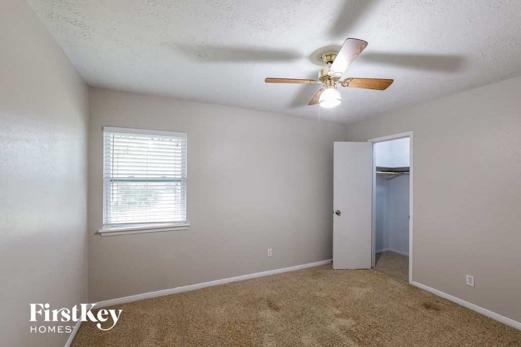 a bedroom with a ceiling fan and a door to a closet