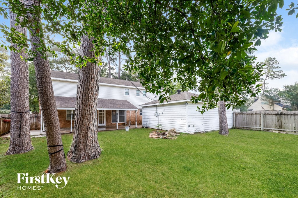 a backyard with a white house and some trees