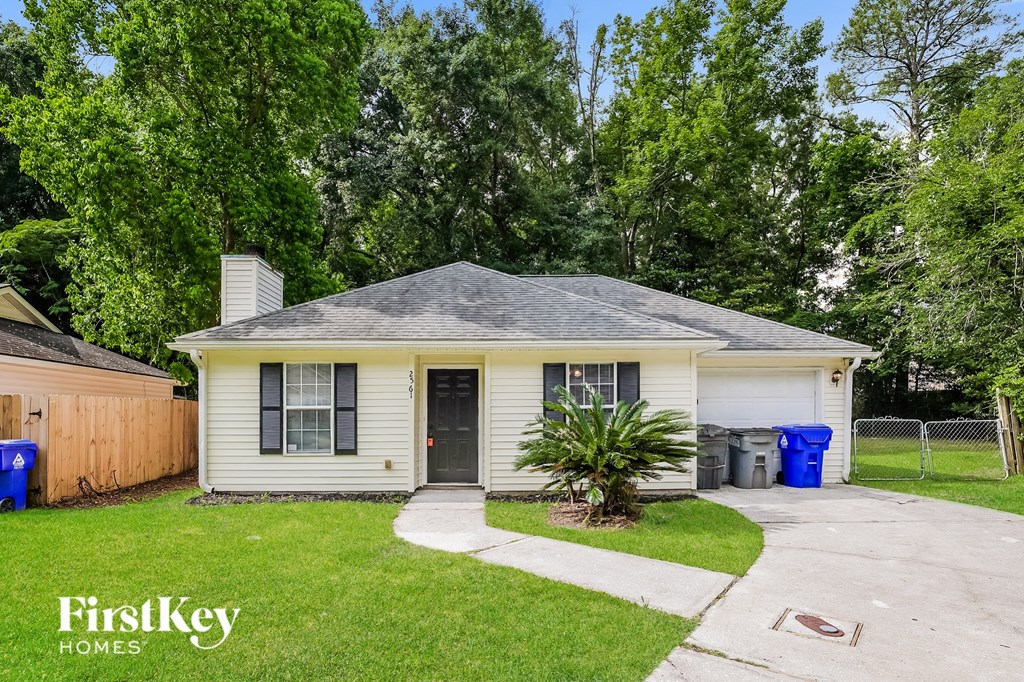 a small white house with a yard and a driveway