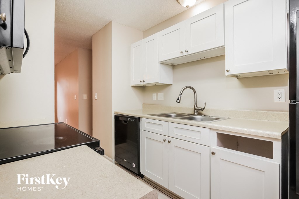 a kitchen with white cabinets and black appliances and a sink