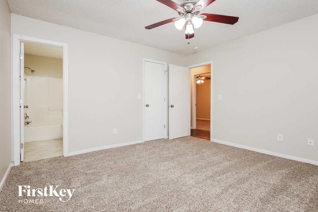 a spacious living room with carpet and a ceiling fan