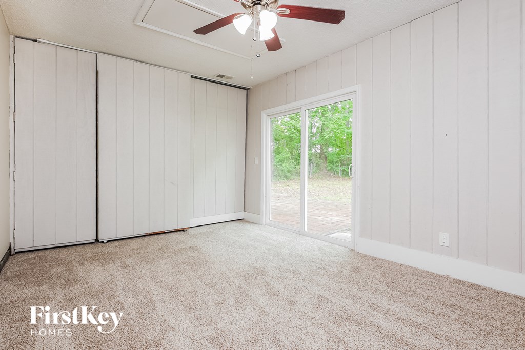 an empty living room with a ceiling fan and a sliding glass door