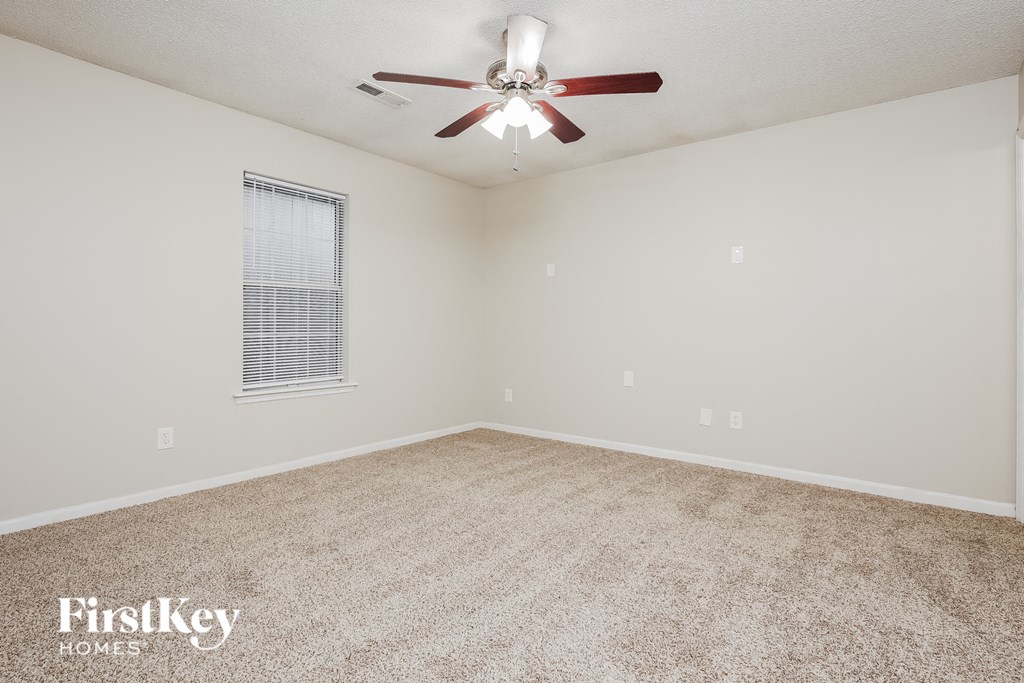 a spacious living room with carpet and a ceiling fan