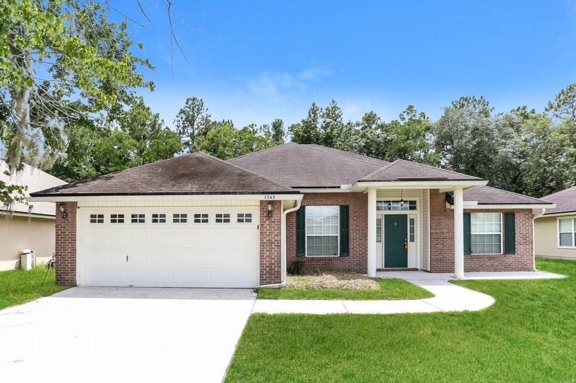 A house with a green door and a grey garage door.
