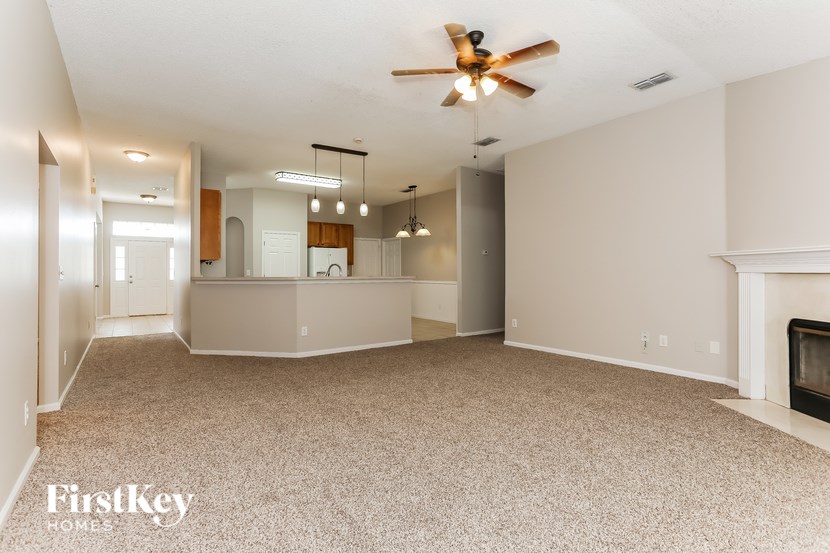A spacious living room with a fireplace and a ceiling fan.