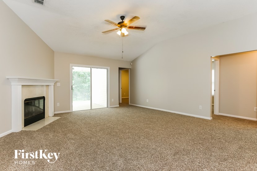 A spacious room with a fireplace and a ceiling fan.
