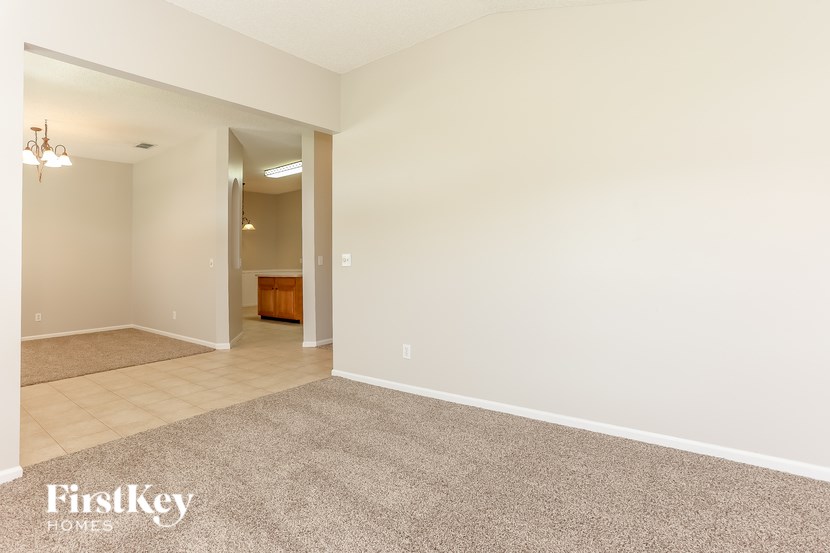 A spacious room with a carpeted floor and a chandelier hanging from the ceiling.