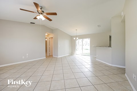an empty living room with a ceiling fan and tiled floor