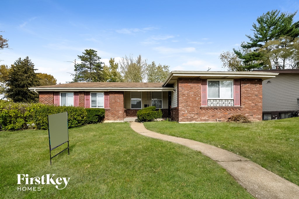 A brick house with a green sign in front of it.