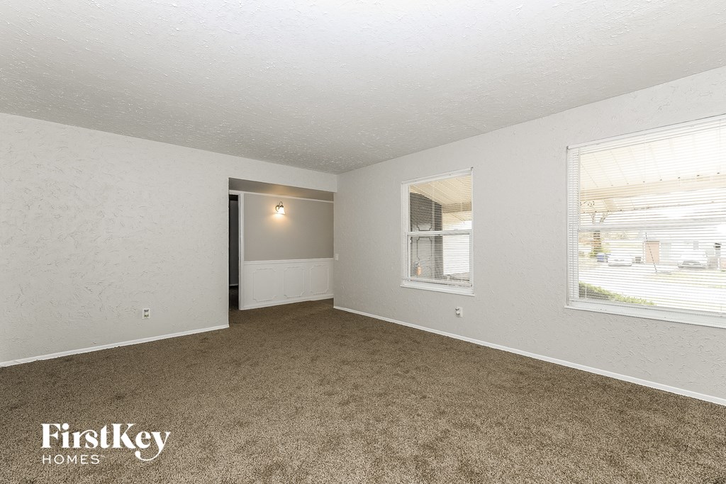 A spacious room with a carpeted floor and a window overlooking a street.
