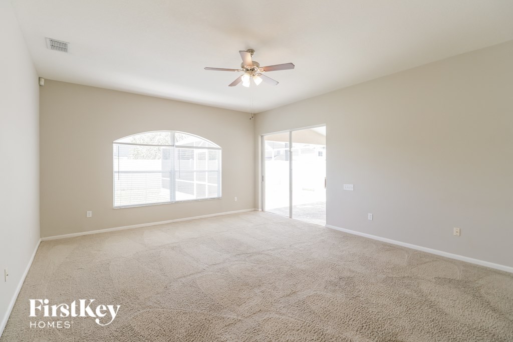 a spacious living room with carpet and a ceiling fan