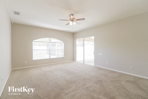 a spacious living room with carpet and a ceiling fan