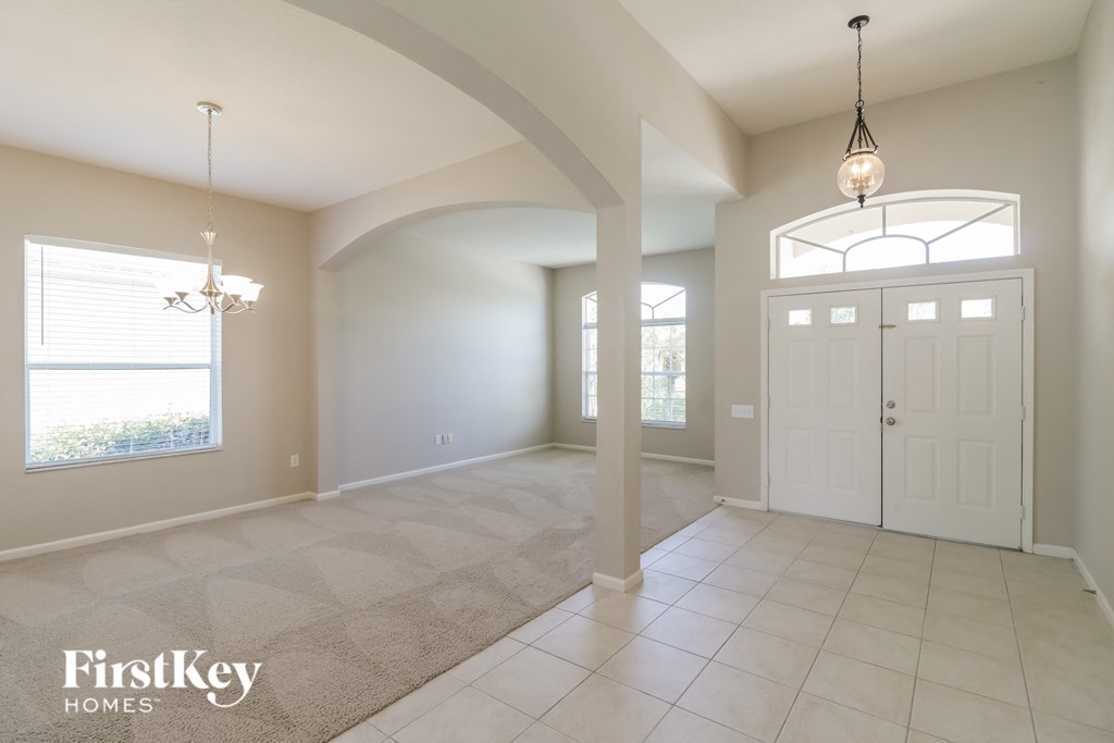 an empty living room and dining room with white doors and windows