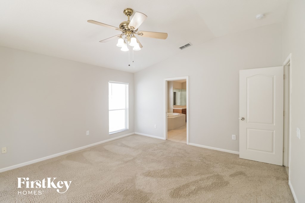 a spacious living room with carpet and a ceiling fan