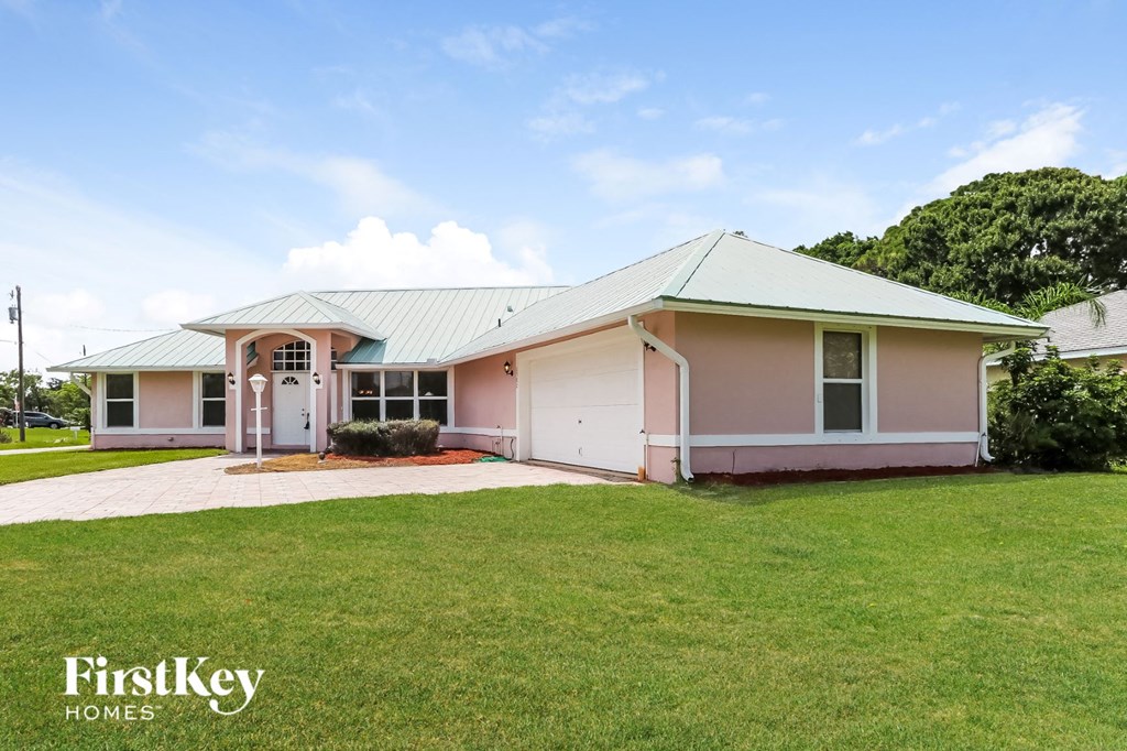 a pink house with a green lawn and a blue sky