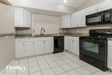 a kitchen with white cabinets and black appliances
