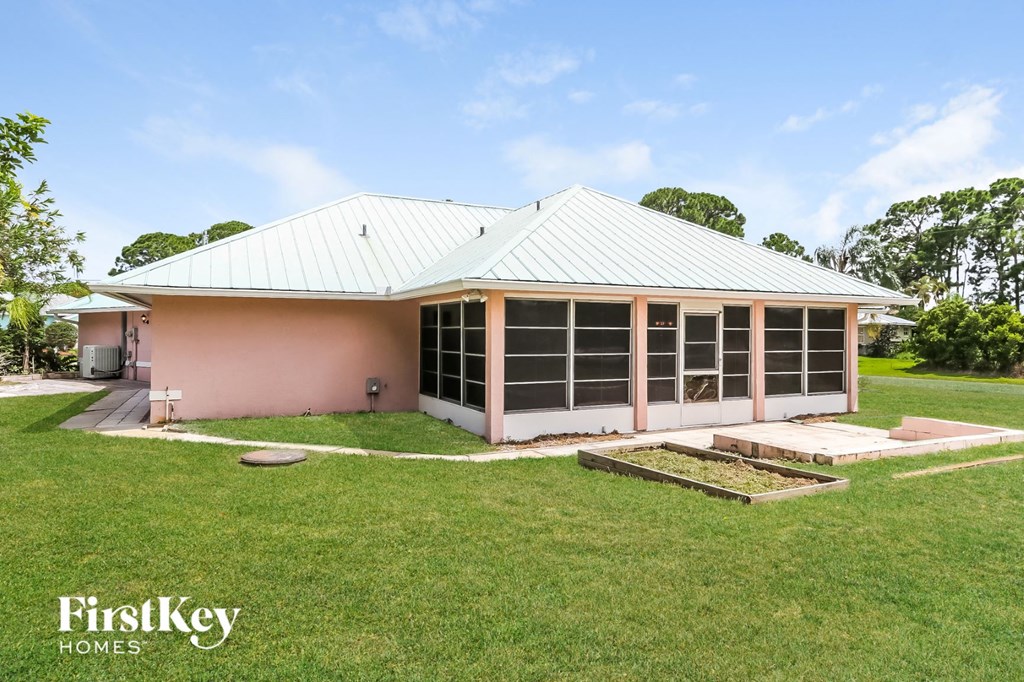 the front of a pink house with a lawn and a porch