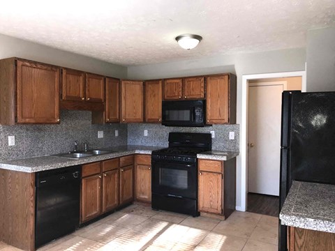 A kitchen with black appliances and wooden cabinets.