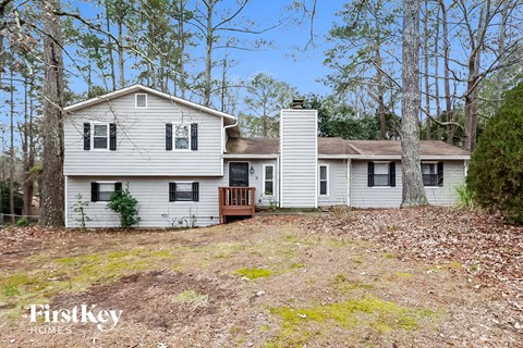 a white house with a yard in the woods