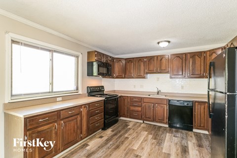 A kitchen with wooden cabinets and a black fridge.