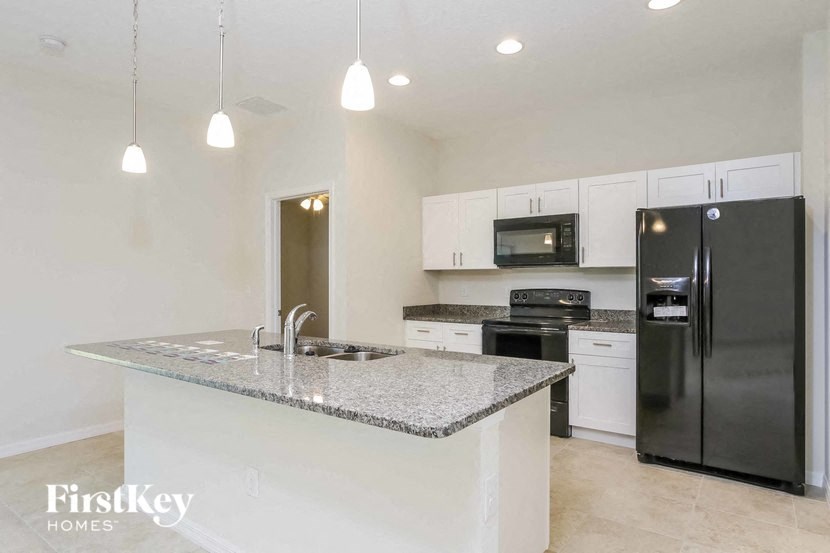 A kitchen with a granite countertop and a black refrigerator.