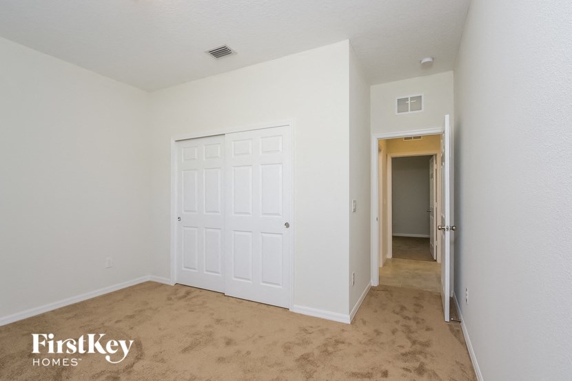 A bedroom with a white door and a carpeted floor.