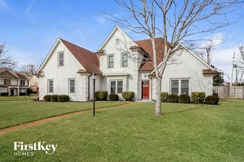 a white house with a yard and a red door