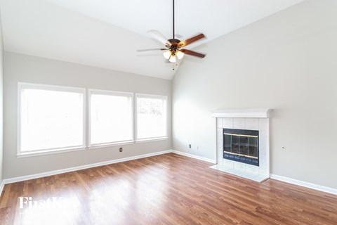 an empty living room with a ceiling fan and a fireplace