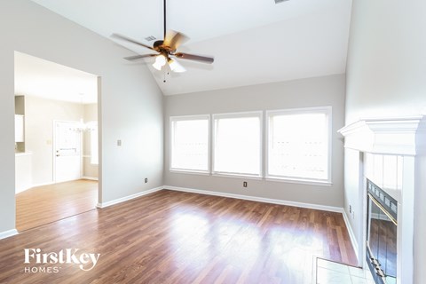 an empty living room with wood floors and a ceiling fan