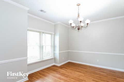 an empty dining room with wood floors and a chandelier