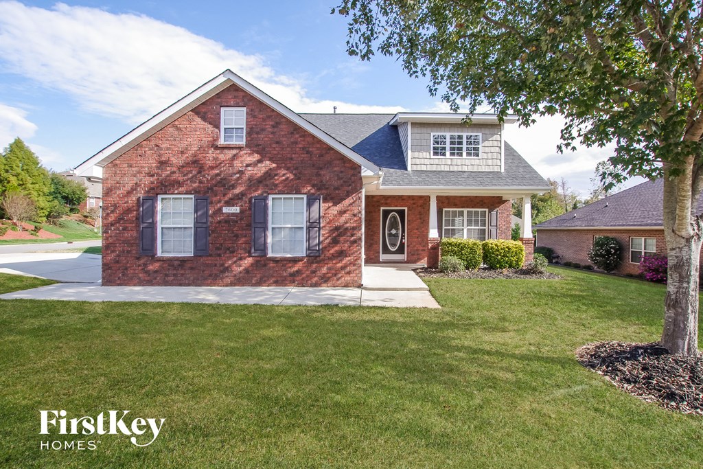 a brick house with a lawn and a tree
