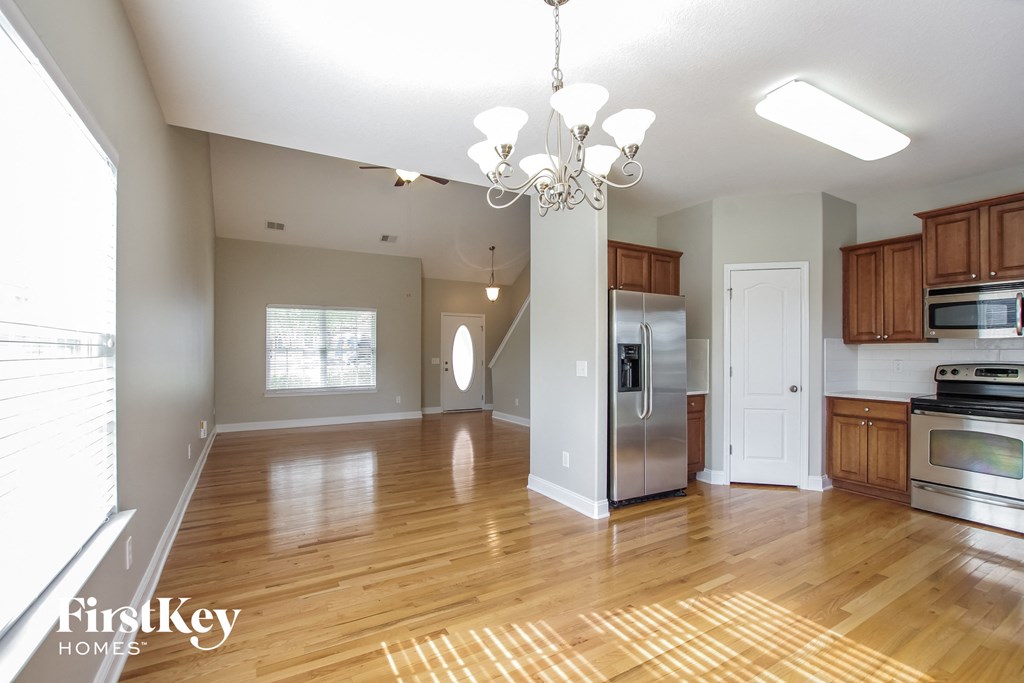 an open kitchen and living room with wood floors and stainless steel appliances