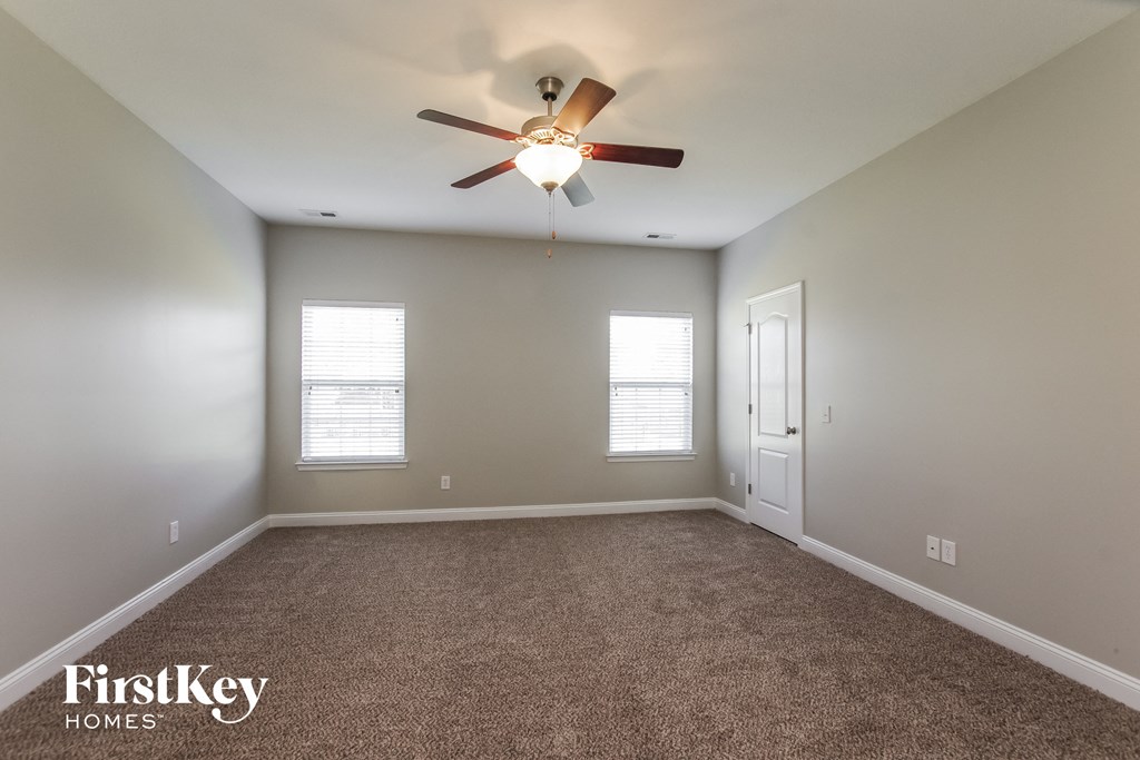 the master bedroom has a ceiling fan and carpeted flooring