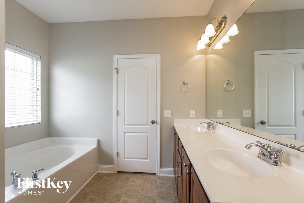 a bathroom with two sinks and a tub and a mirror