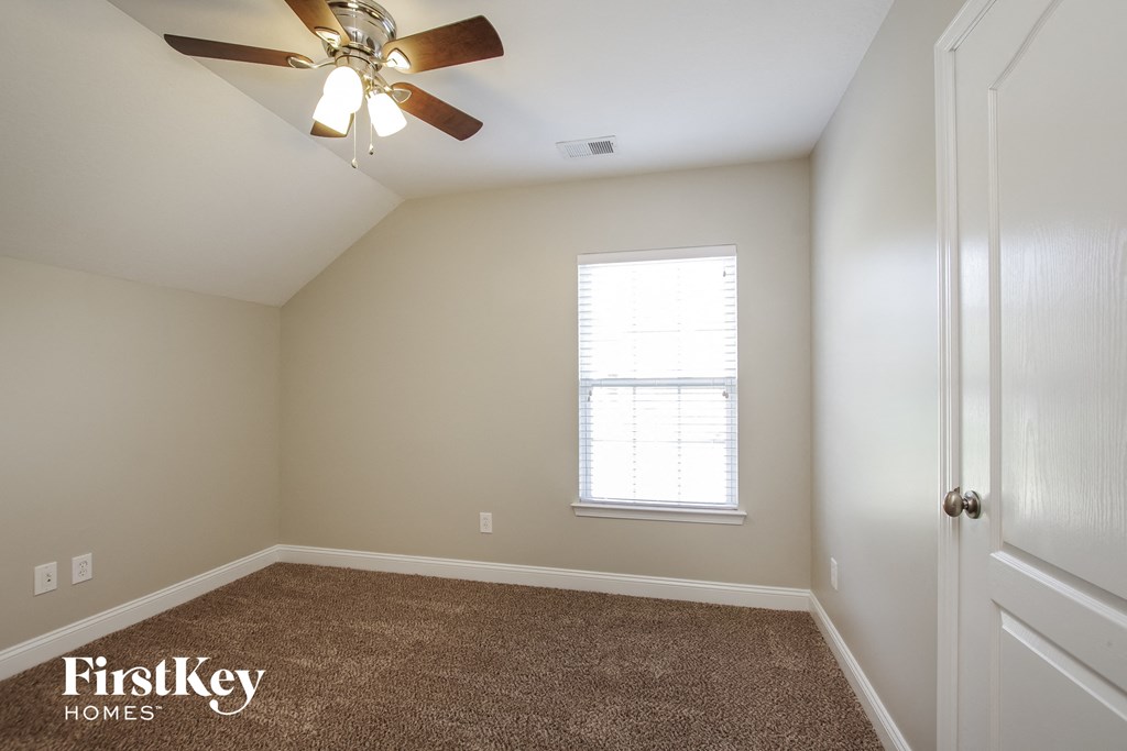 an empty room with a ceiling fan and a window