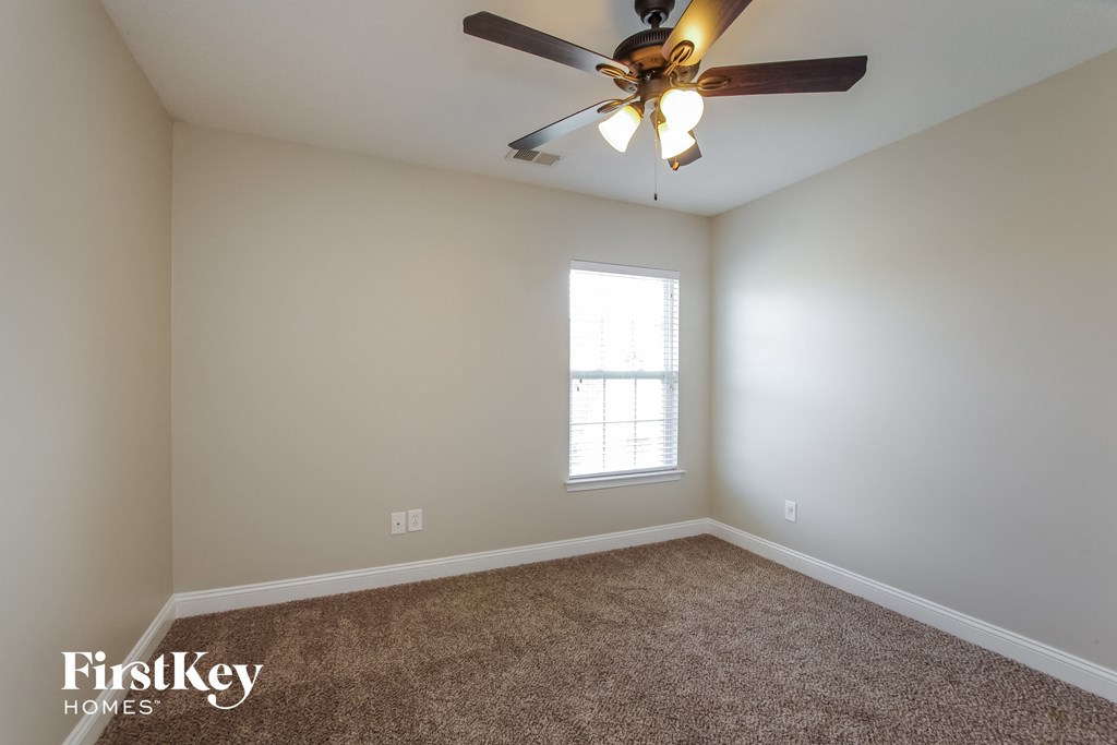 an empty room with a ceiling fan and a window