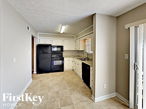 A kitchen with black appliances and white cabinets.
