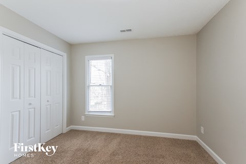 a bedroom with a carpeted floor and a window and a closet