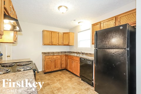 A kitchen with a black fridge and wooden cabinets.