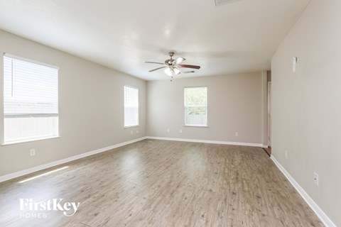 A spacious room with a ceiling fan and wooden flooring.
