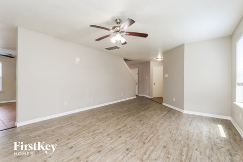 A spacious room with a ceiling fan and wooden flooring.