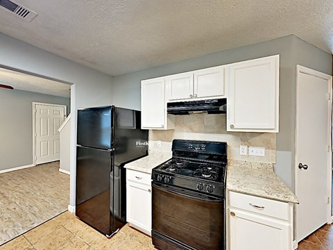 A kitchen with a black refrigerator and stove top oven.