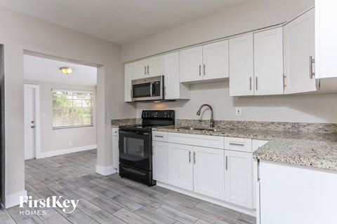 A kitchen with white cabinets and a granite countertop.